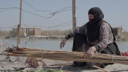 سيدة تقوم بشواء السمك على القصب